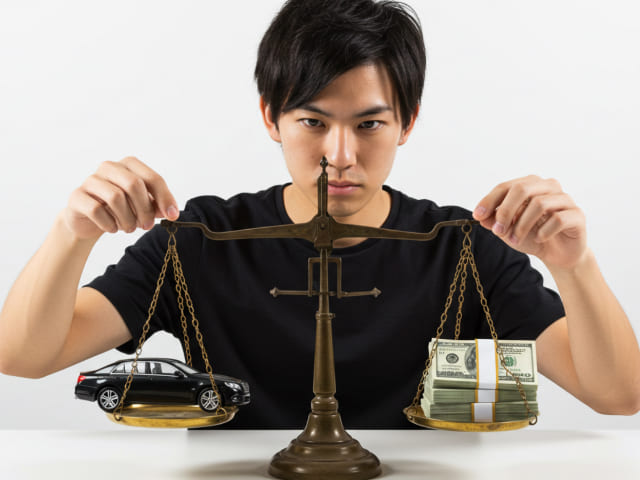 車とお金を天秤にかける男性